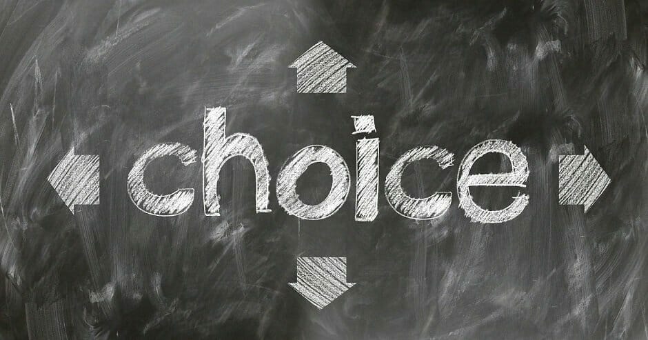 The paradox of choice - choice written in white chalk on blackboard with four arrows going outwards from it