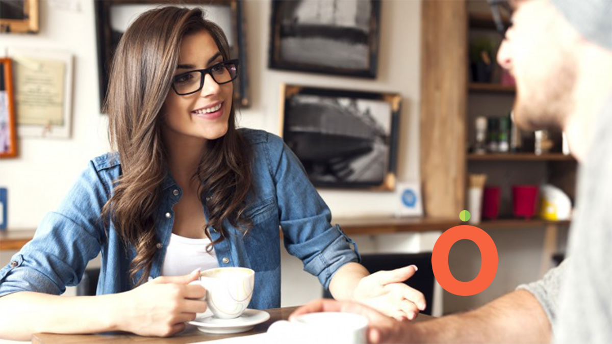 Millennial woman happily networking with contact over coffee.