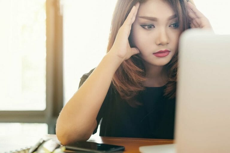 Shocked woman sitting at computer in disbelief from bad career advice.
