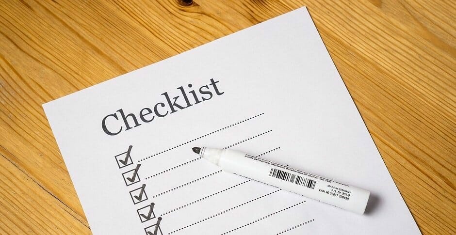 Checklist with checked checkboxes and marker on desk.