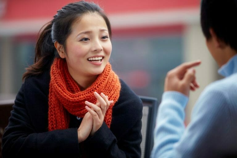Enthusiastic young woman in conversation wearing an orange scarf.
